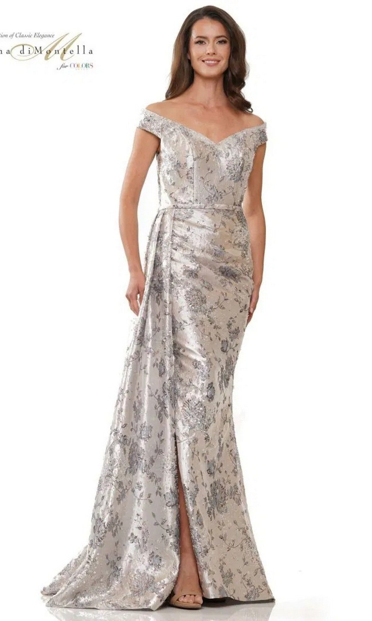 A woman models the Rina Di Montella RD2912 long formal dress, featuring an off-the-shoulder jacquard design with a silver and gray floral pattern and front slit, standing against a plain white background.